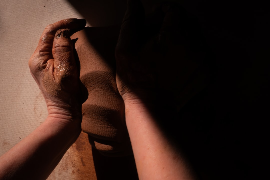 The maker's hands covered in clay, showing the tactile reality of daily ceramics work