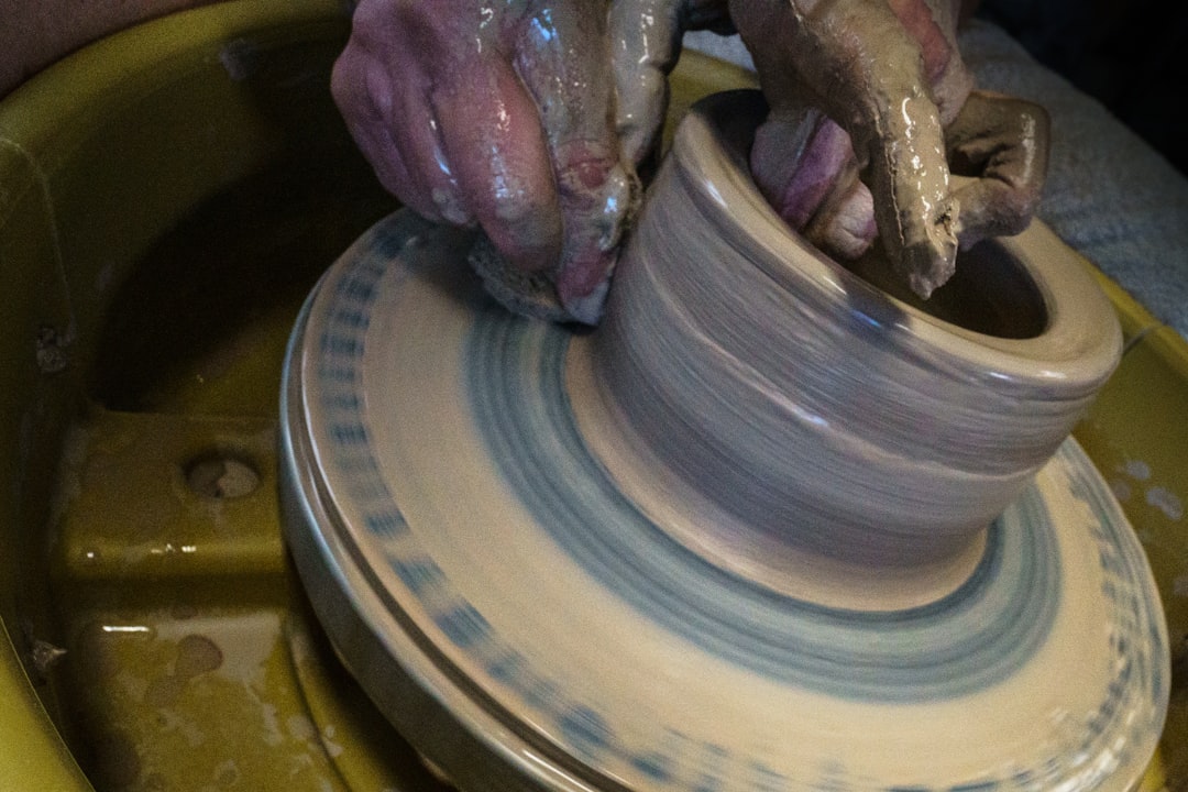 Textured clay background showing hands working on pottery wheel
