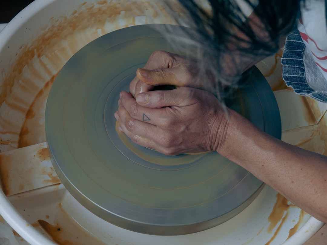 Hands shaping wet clay on a pottery wheel in the Jalan Besar studio