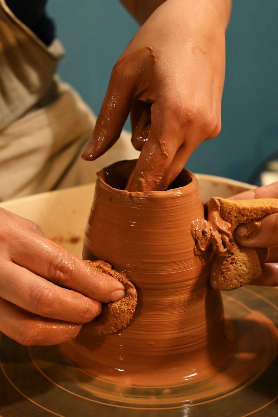 Potter's hands shaping clay on the wheel in the studio